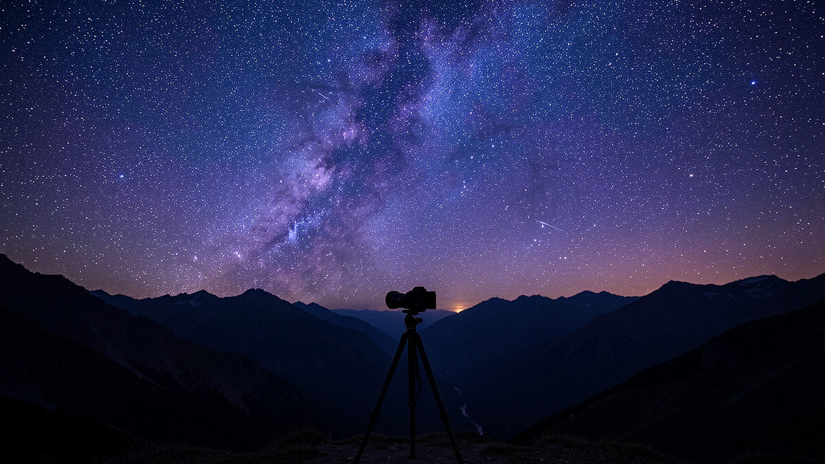 Fast wide-angle prime lens on a mirrorless camera on a tripod under a star field