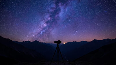 Fast wide-angle prime lens on a mirrorless camera on a tripod under a star field
