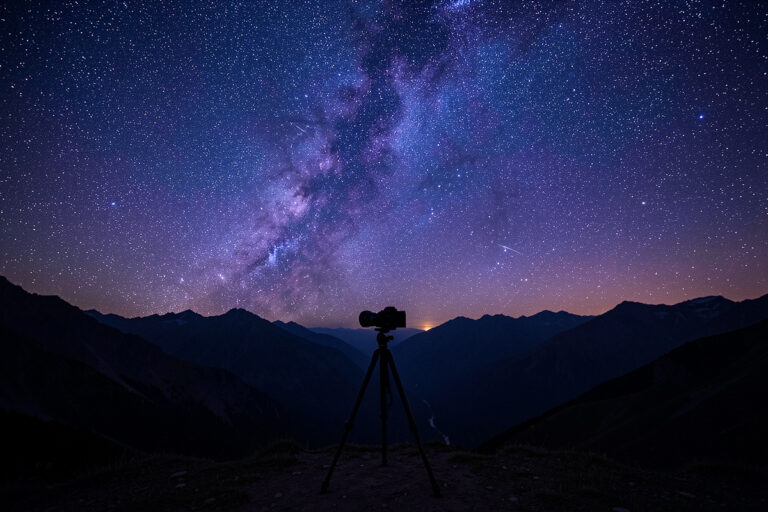 Fast wide-angle prime lens on a mirrorless camera on a tripod under a star field