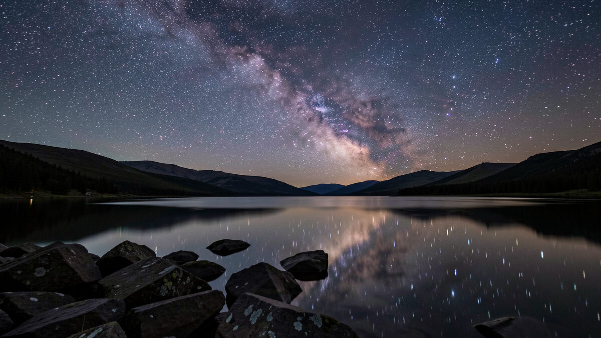 Wide-angle lens framing the Milky Way over a dark landscape horizon