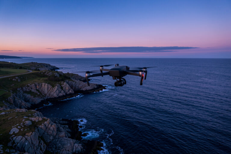 Camera drone hovering over a Swedish coastline at blue hour for aerial photography