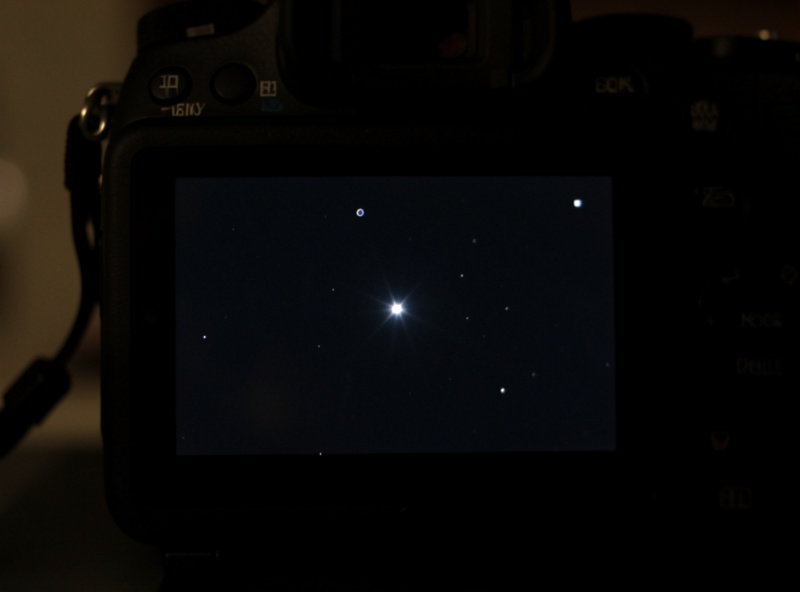 A camera rear screen showing a magnified bright star being manually focused to a small point