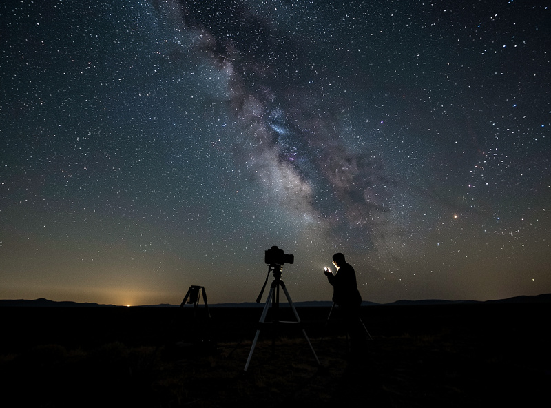 Astrophotographer shooting the Milky Way at night with a DSLR on a tripod, where DSLRs still hold advantages