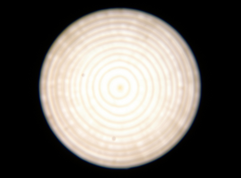 Single out-of-focus bright disc filled with fine concentric onion-ring texture