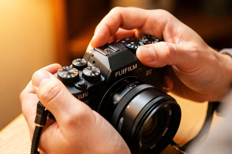 Photographer adjusting manual exposure on a mirrorless camera for video