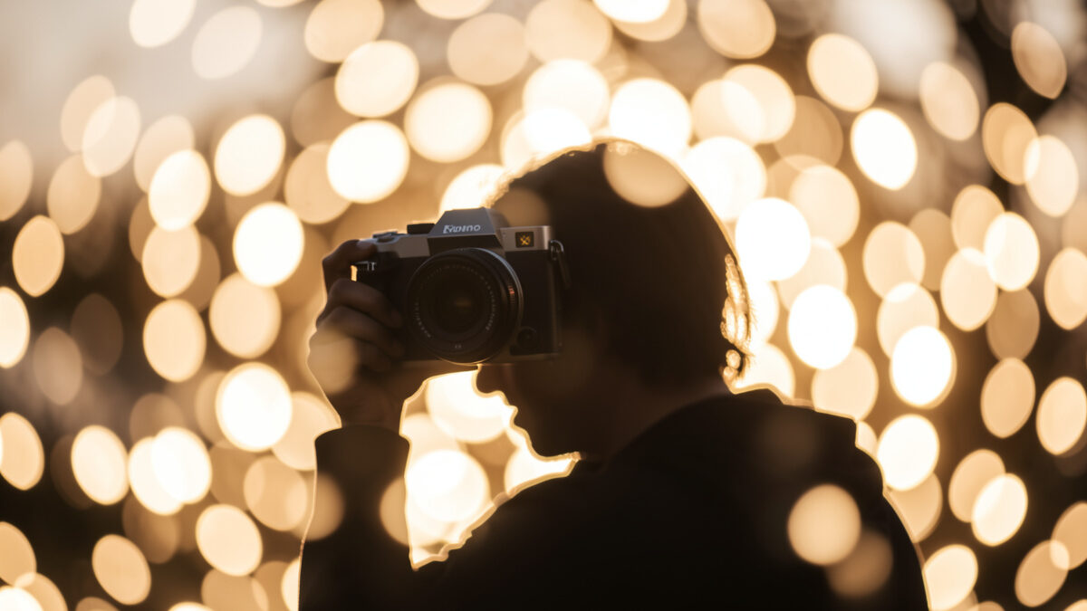 Portrait prime lens on a mirrorless camera rendering a subject into large creamy bokeh highlights at golden hour