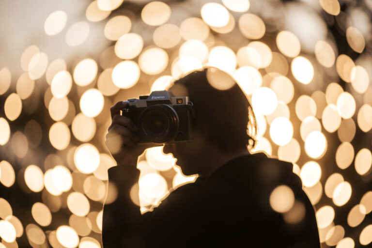 Portrait prime lens on a mirrorless camera rendering a subject into large creamy bokeh highlights at golden hour