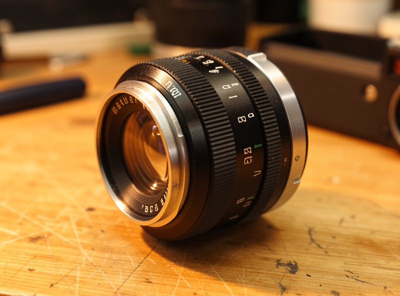 M42 vintage prime mounted on a mirrorless body via a dumb adapter ring on a wooden workbench