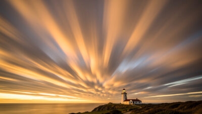 Long exposure of streaking clouds over a lighthouse with radial streaks toward the horizon