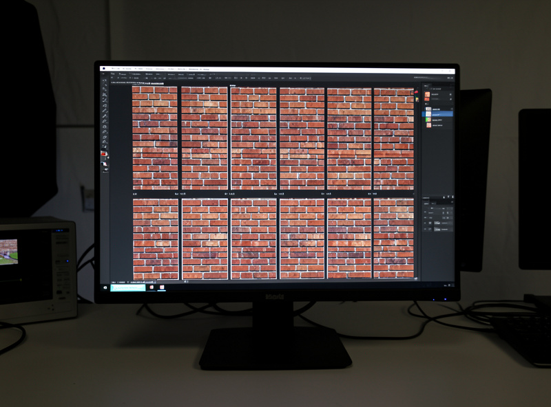 Calibrated monitor displaying a grid of the same brick-wall frame shot at several different apertures for comparison