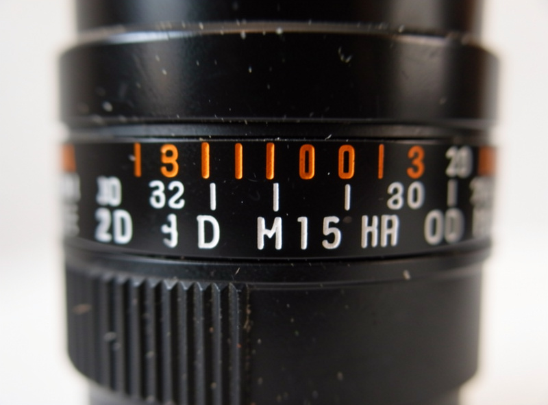 Vintage lens barrel showing the engraved distance and depth of field scale used for zone focusing