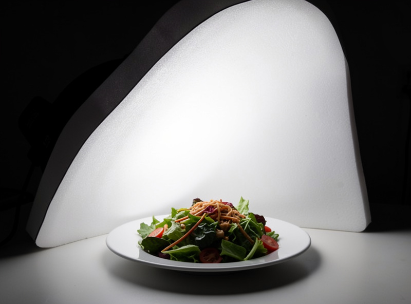 A side-lit bowl of ramen near a window showing steam and directional shadows falling away from the light