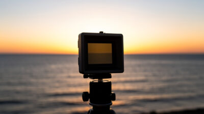 A graduated ND filter in a square holder darkening a bright sky over a sea horizon