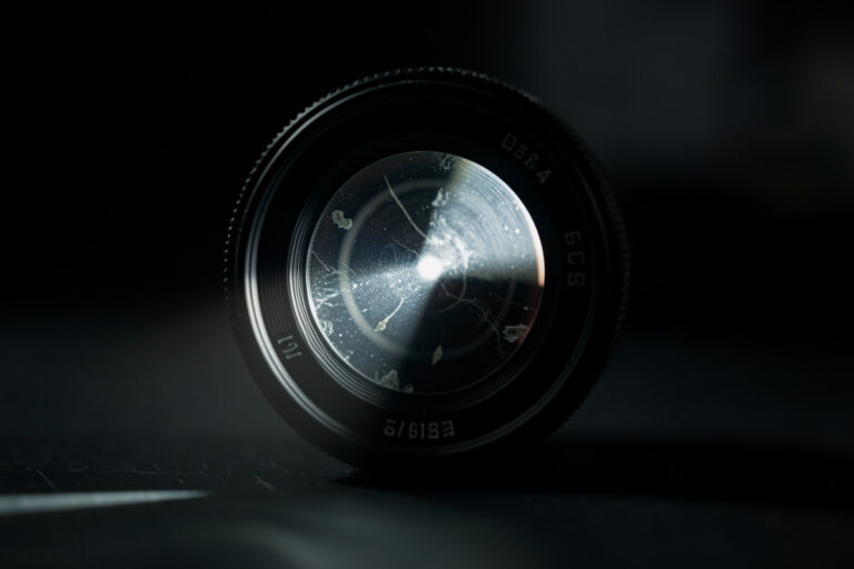 Camera lens lit by a single beam revealing internal contamination