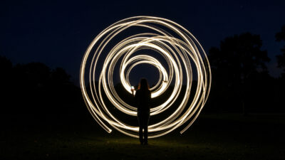 Long exposure light painting of glowing swirling light trails drawn in the air at night