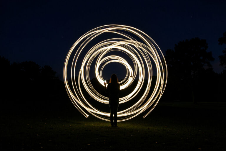 Long exposure light painting of glowing swirling light trails drawn in the air at night