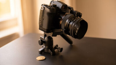 Geared macro focus rail clamped to a tripod with a mirrorless camera aimed at a small engraved coin