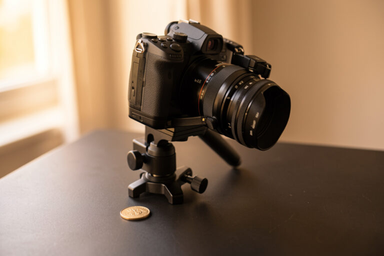 Geared macro focus rail clamped to a tripod with a mirrorless camera aimed at a small engraved coin