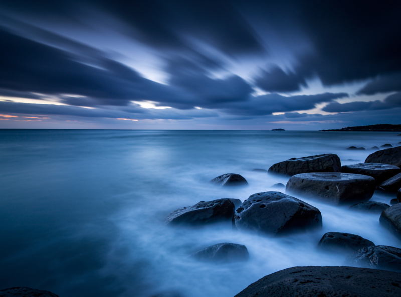 Long-exposure seascape with smooth misty water and streaked clouds shot with a 10-stop ND filter