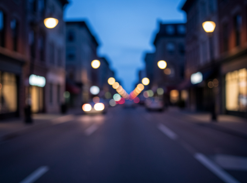 Handheld dusk street scene with slight motion blur in the streetlights, a subtly soft frame in blue-hour light