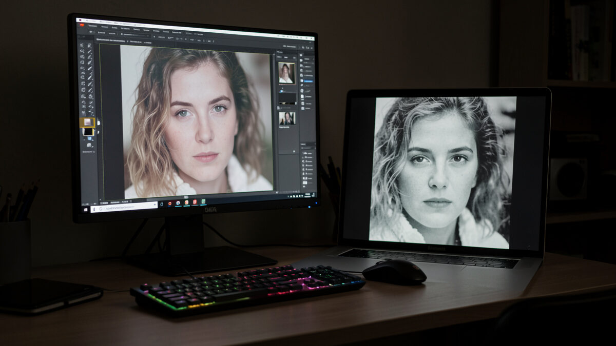 Calibrated monitor showing a magnified soft photo beside a sharp one on an editing desk